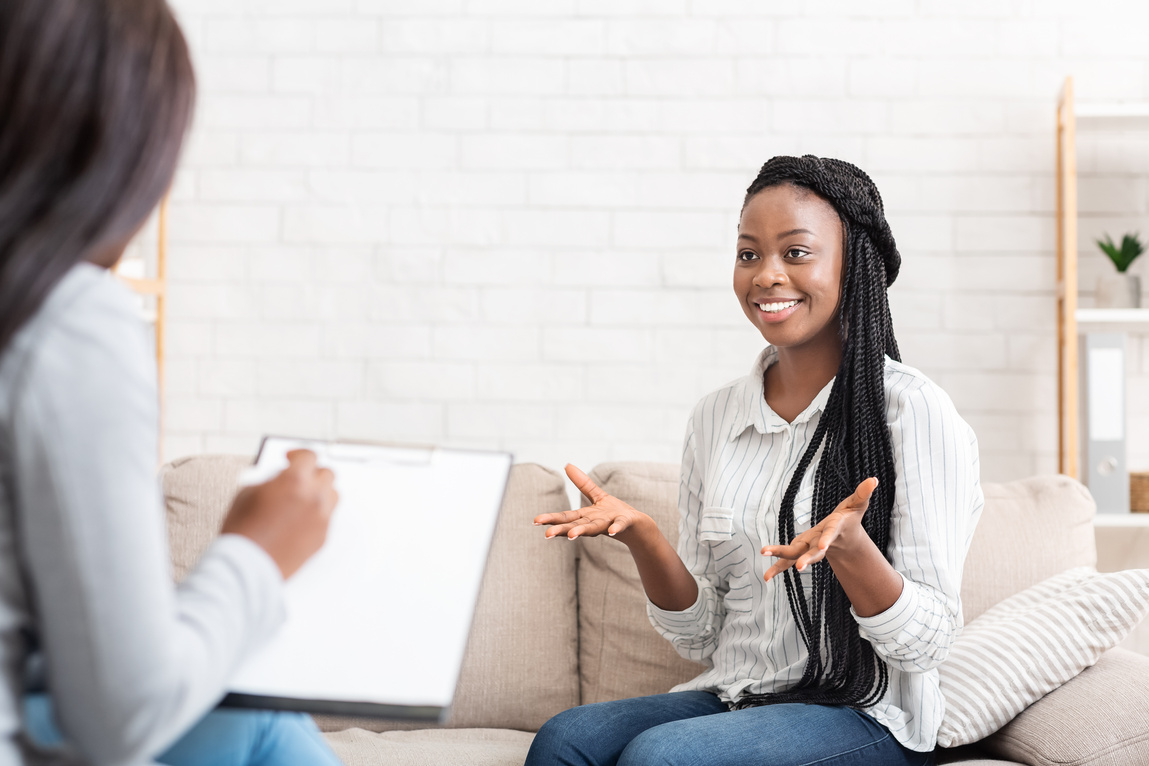 Happy black woman talking to psychologist after successful therapy session